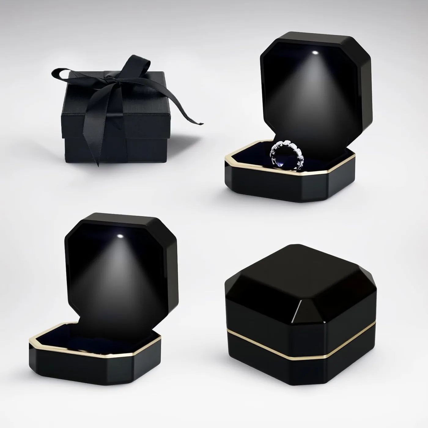 Black octagonal LED ring box open with the light on next to a black ribboned gift box