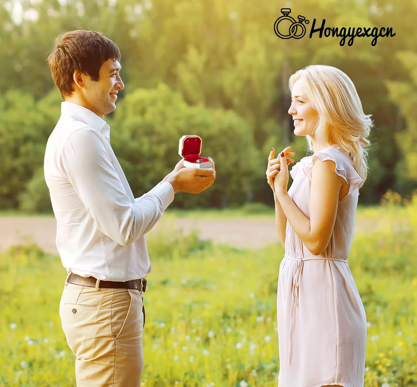 Man holding an open ring box with a red interior toward a woman outdoors during a proposal